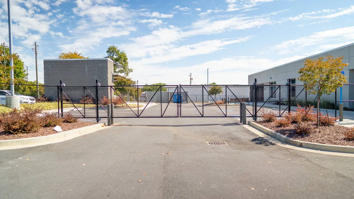 Closed chain-link gate at a commercial property entrance with clear blue skies.