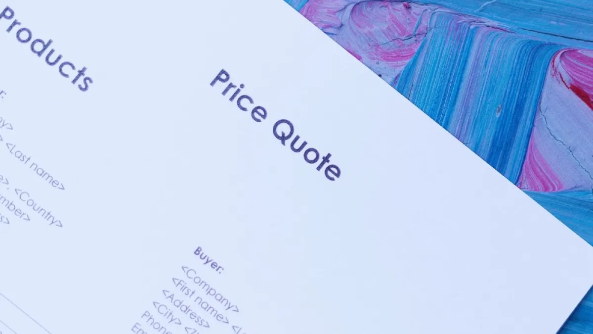 Close-up of a printed price quote document on a colorful blue and pink painted surface.