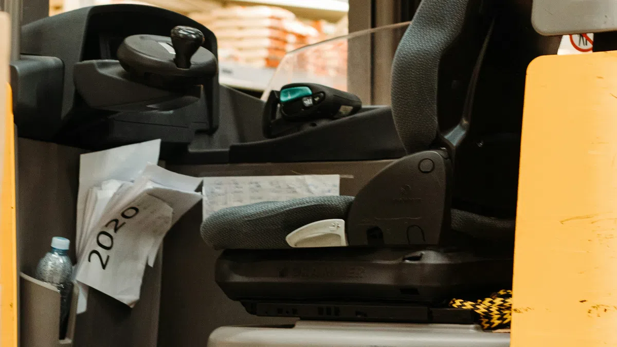 Close-up of a Jungheinrich forklift operator seat inside a warehouse with stacked goods in background.
