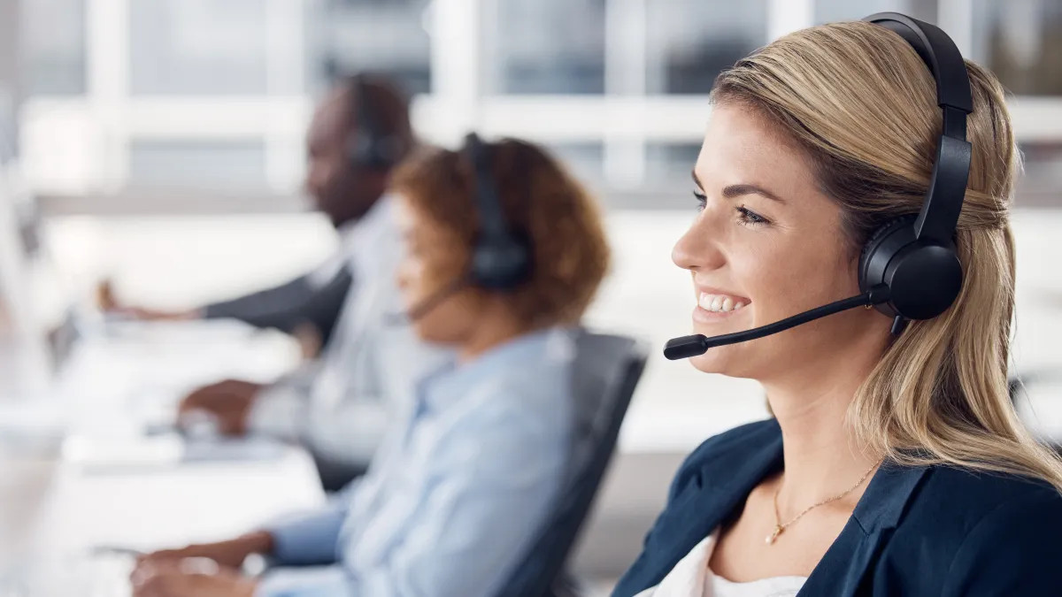 Smiling customer service representative wearing a headset working in a modern office environment