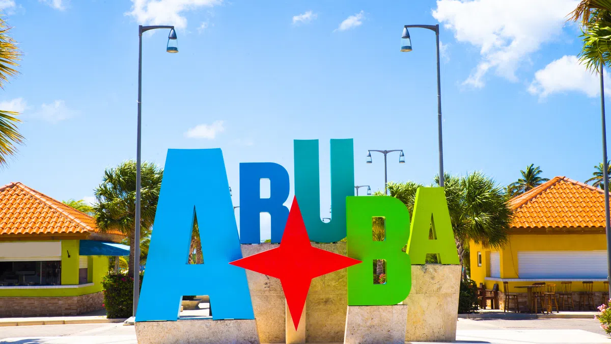 Colorful Aruba sign with large letters and a red star under clear blue sky in a tropical setting.