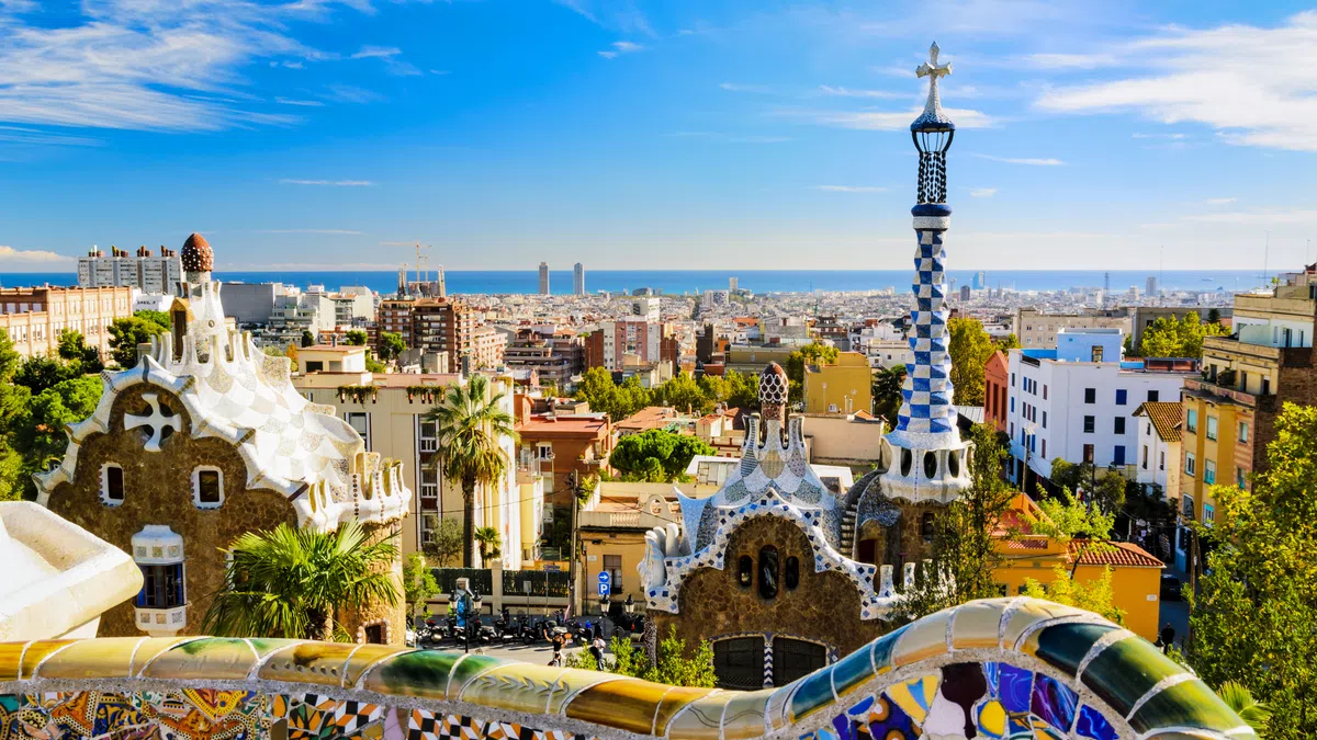 Colorful mosaic benches overlooking Barcelona cityscape with unique architecture and Mediterranean Sea in the background