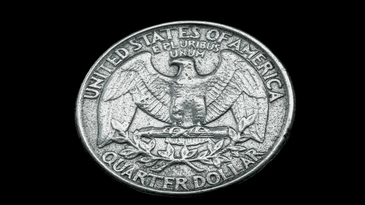 Reverse side of a United States quarter dollar featuring an eagle and inscriptions on a black background