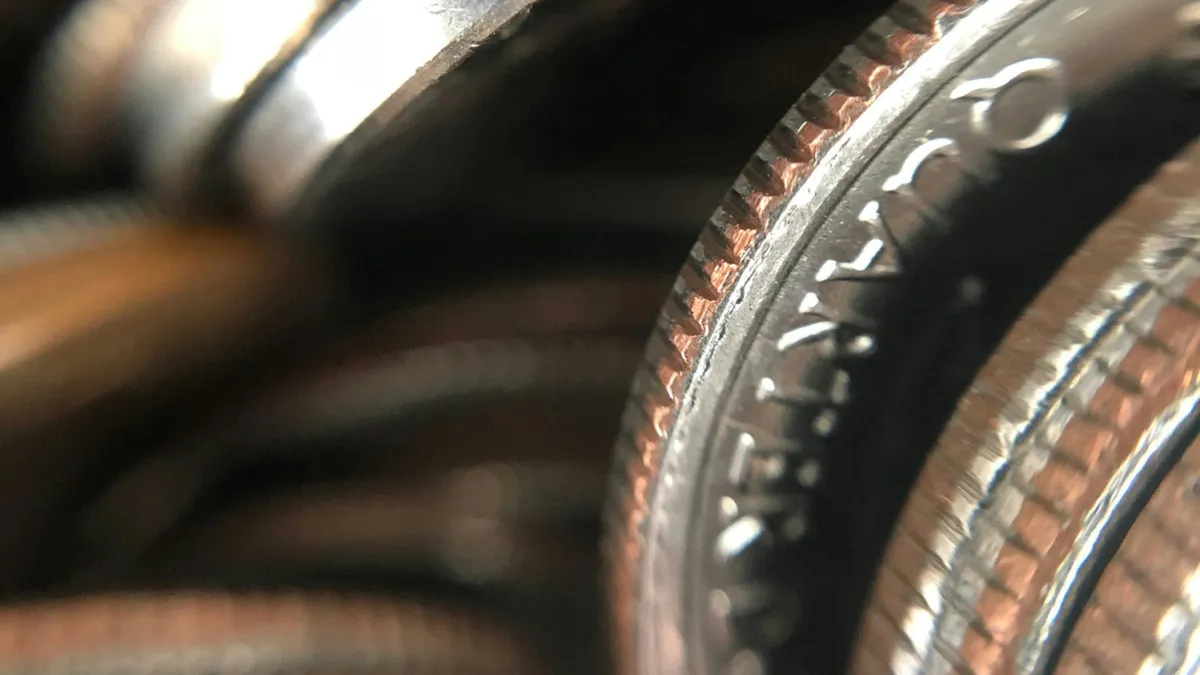 Close-up of stacked quarters showing coin edges and partial text with metallic texture and reflections.
