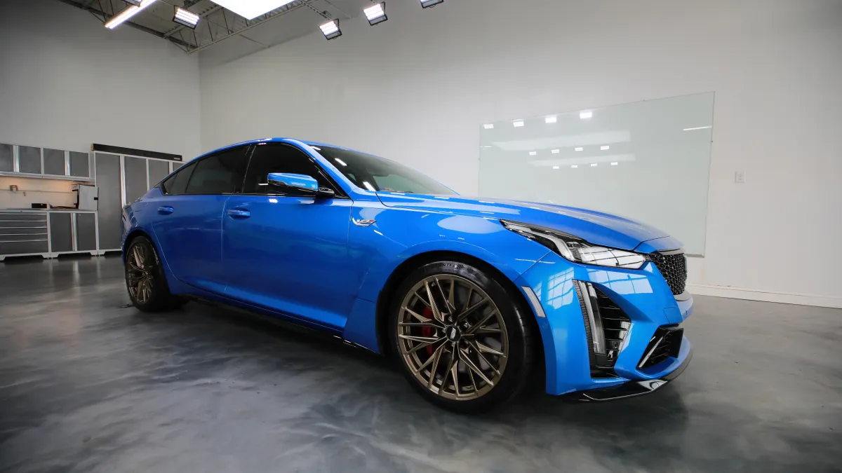 Sleek blue sports sedan parked in a modern, well-lit garage with polished concrete floors.