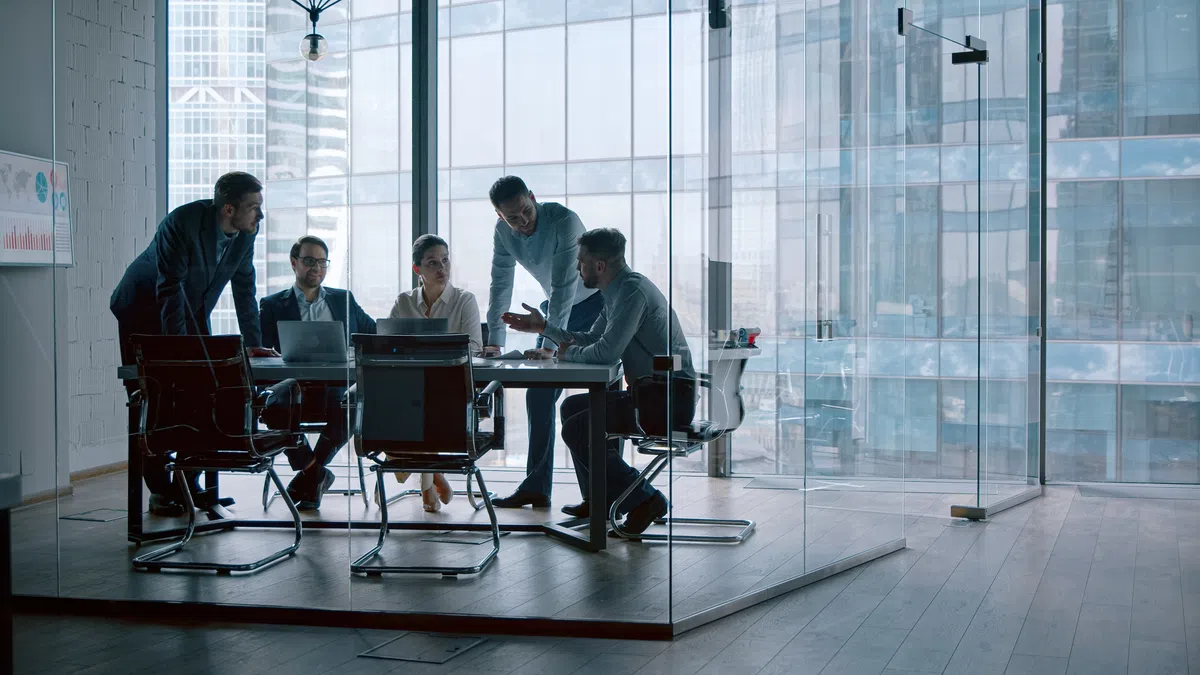 a group of people sitting at a table with laptops