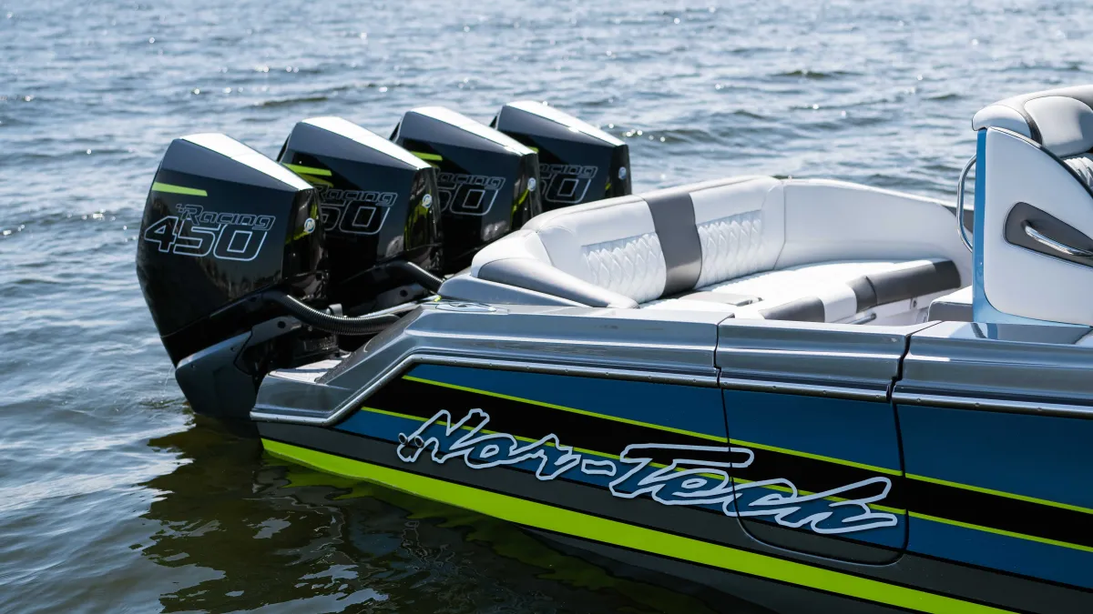 Rear view of a Nor-Tech speedboat with four powerful 450 horsepower engines on calm water under a clear sky.