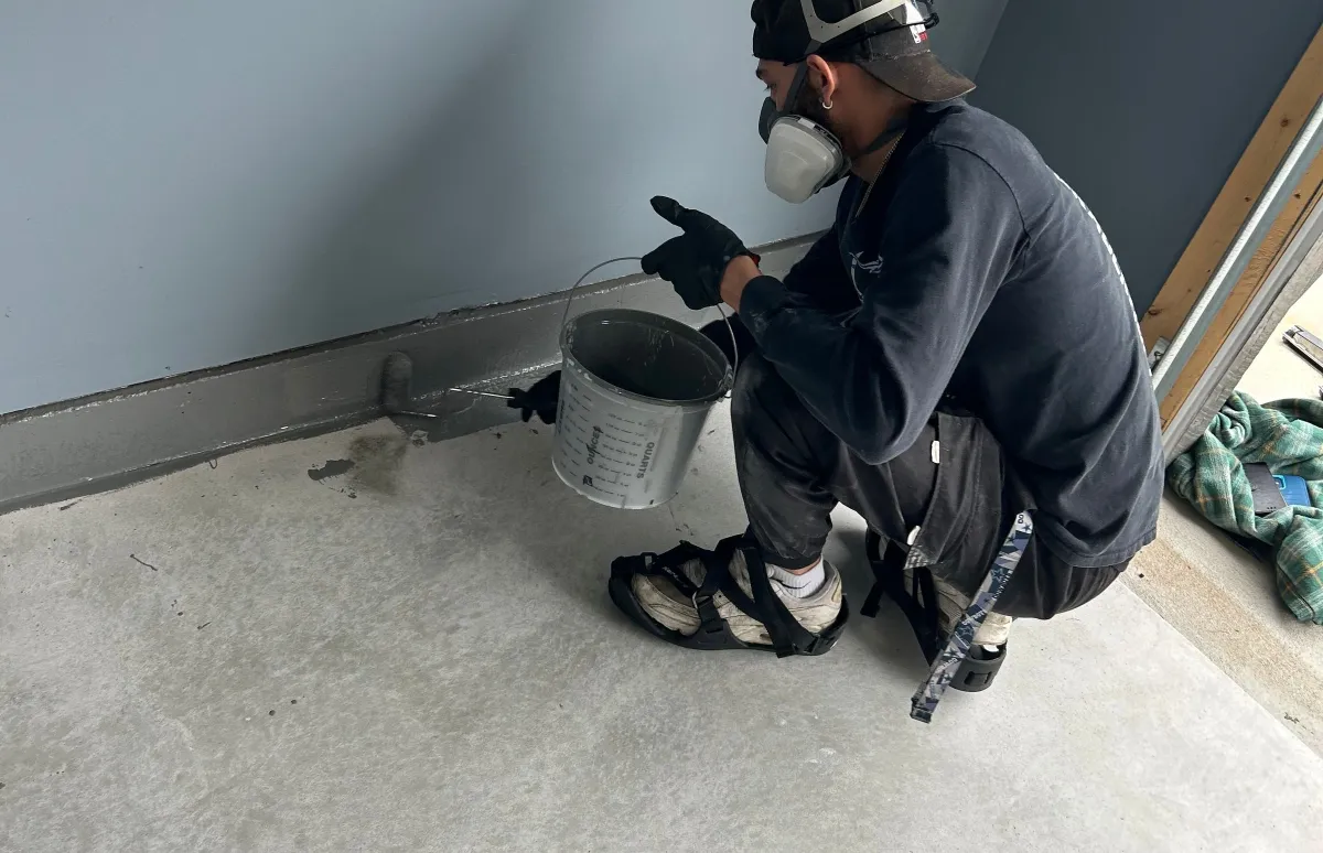 man applying base coat to garage floor