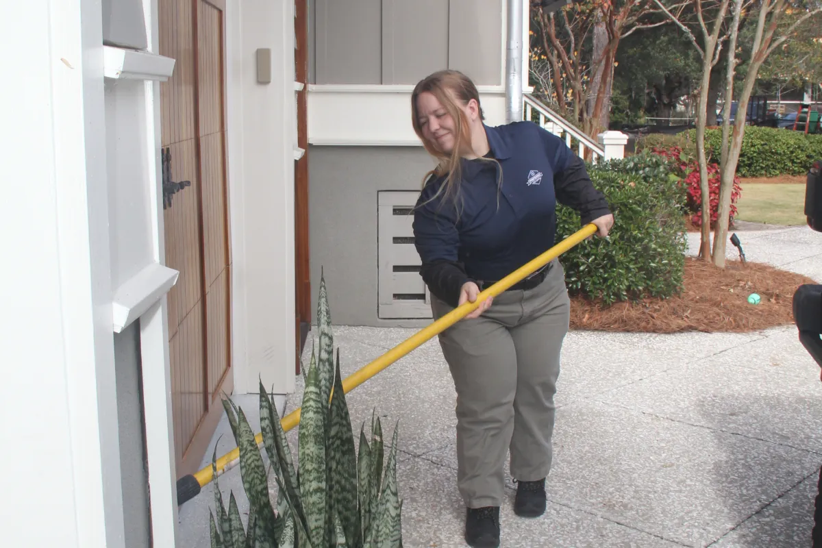 a person holding a broom outside a house