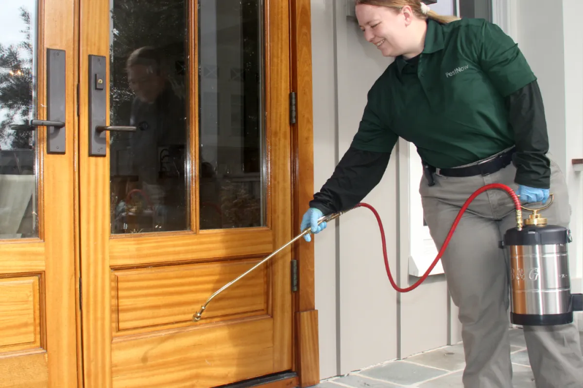 lady spraying outside the home for pests