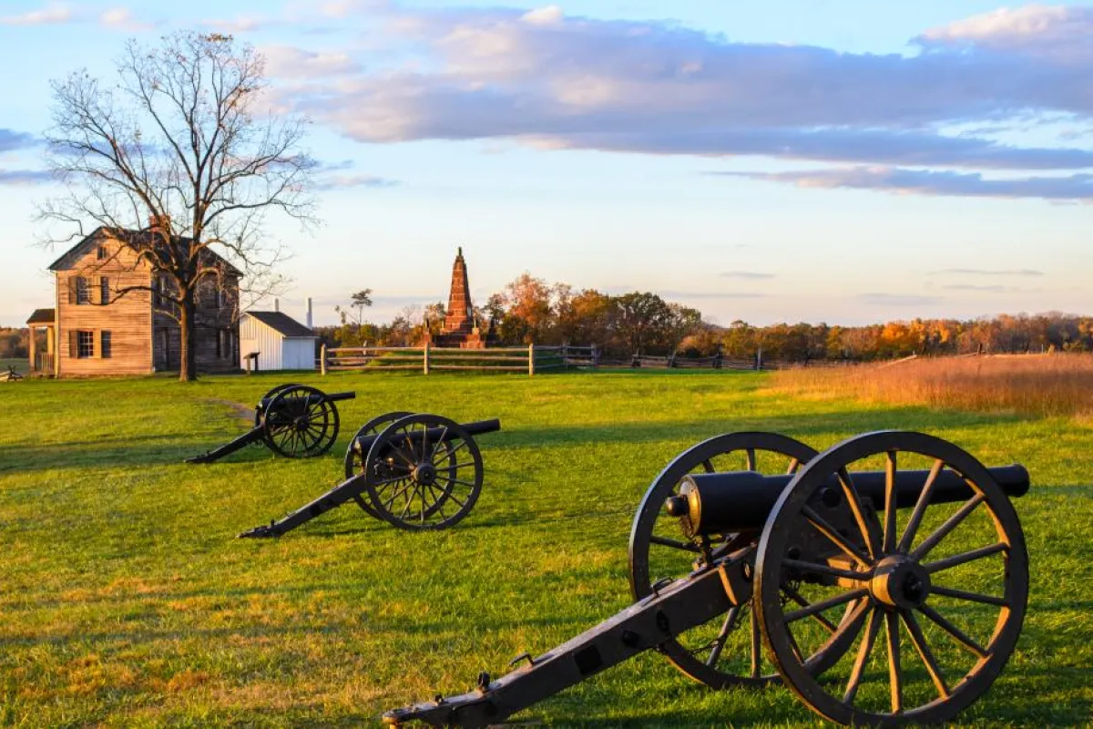 a row of cannons on a grass field with a church in the background