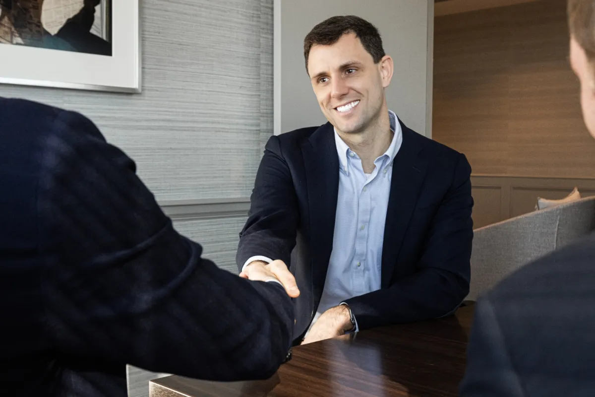 a man in a suit sitting at a table with another man in a suit