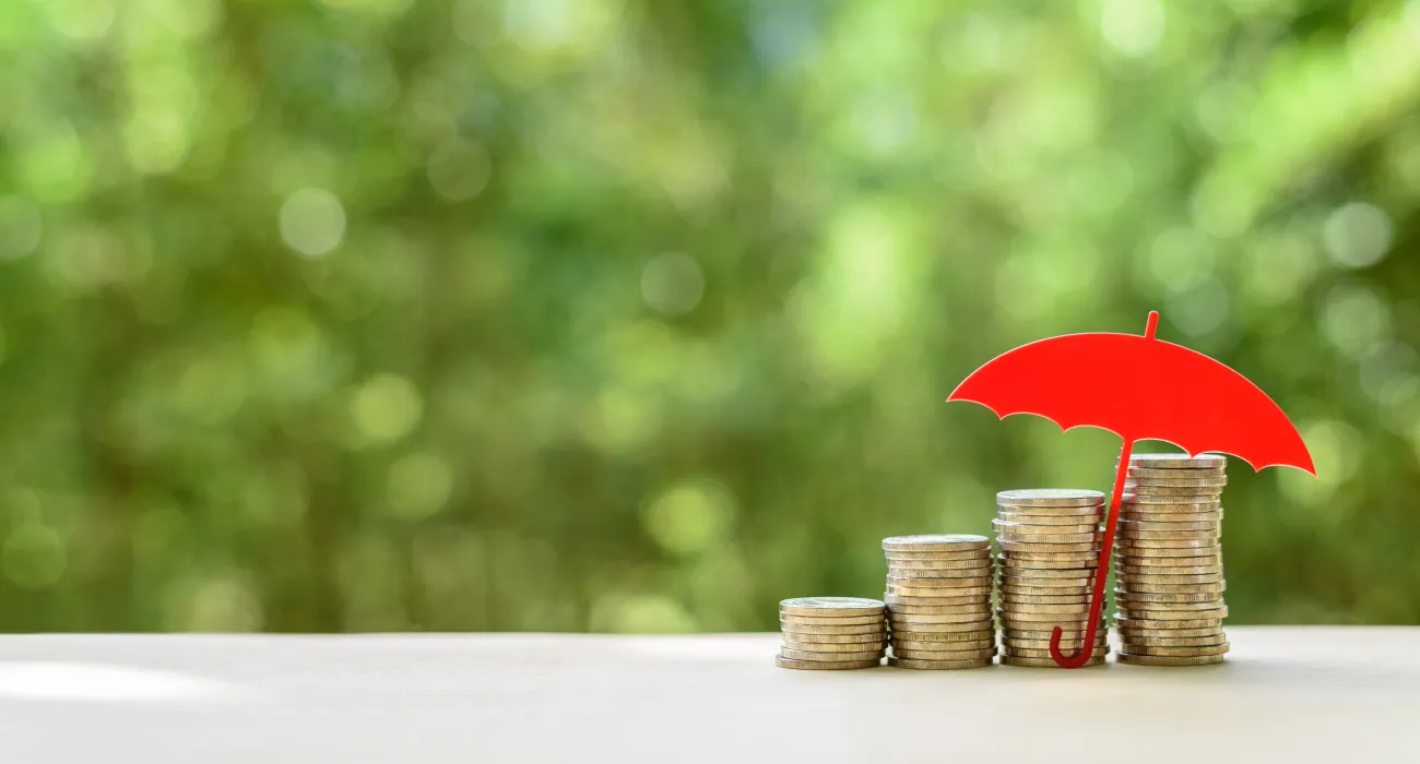 a red umbrella over stacks of coins