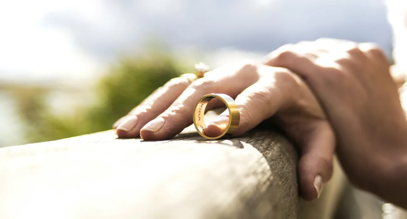 a close-up of hands holding a gold ring