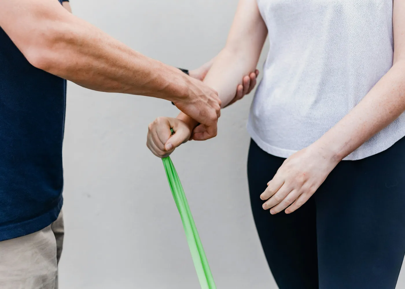 Physical therapist assisting patient with green resistance band arm exercise for rehabilitation.