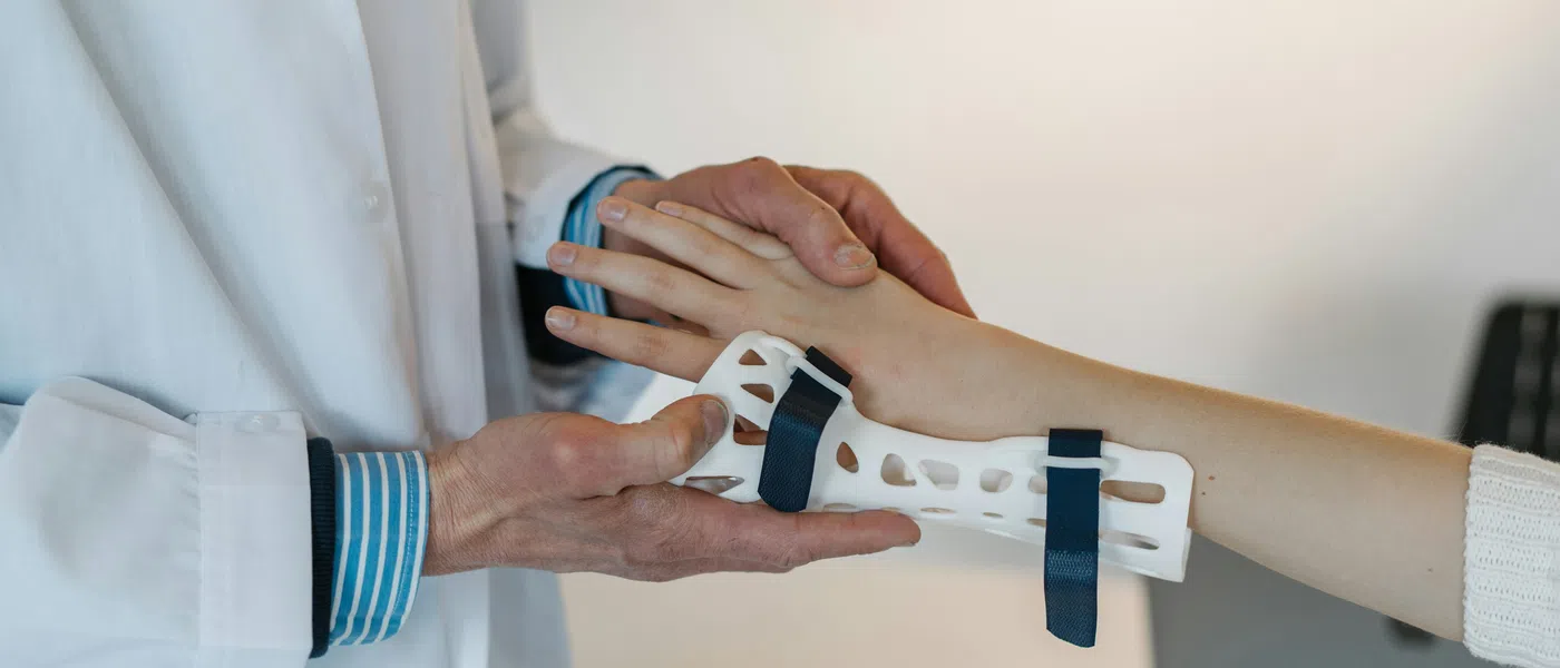 Doctor fitting a wrist brace on patient's hand to support and immobilize the wrist during recovery.