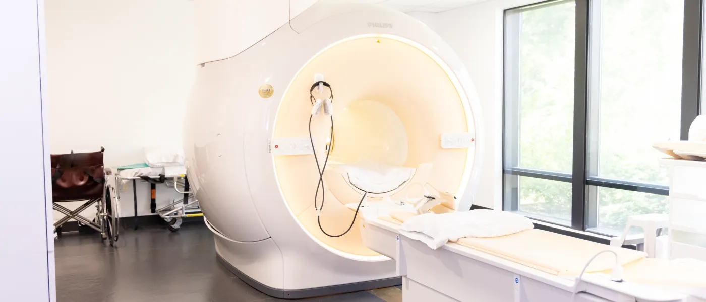 Modern MRI machine in a bright, sterile medical room with a patient bed and medical equipment.
