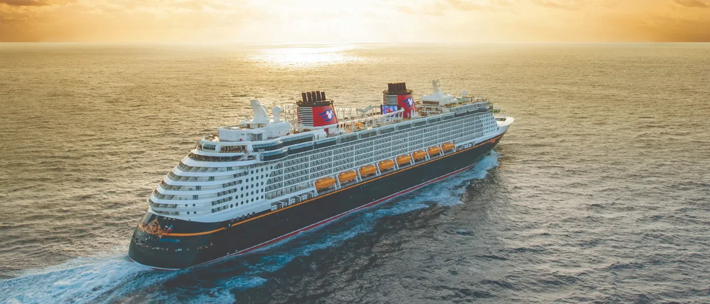 Large cruise ship sailing on calm ocean waters at sunset under partly cloudy sky
