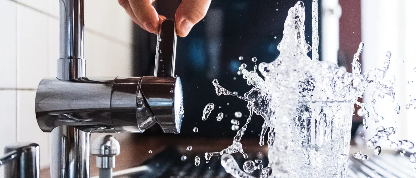 a hand pouring water into a faucet