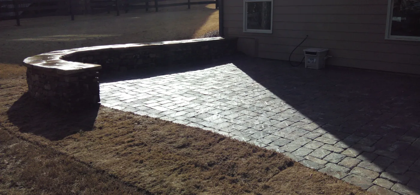 Paver patio with short stone wall and cap.