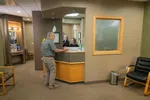 Man checking in at a dental office reception desk with staff assisting in a welcoming waiting room.