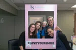 Five smiling dental staff posing behind a pink frame with #LOVEYOURSMILE at Levenson Smile clinic.