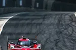 Red Acura race car speeding on a curved race track with tire marks and concrete barriers in the background