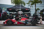 Red and black Acura race car number 40 in pit lane with crew and black Acura DEX Imaging tents in background.