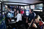 Race team engineers and strategists monitoring multiple screens and data during a motorsport event in a dimly lit control room.