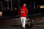 Worker in red jacket painting red line on asphalt parking lot at night under streetlights.
