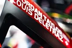 Close-up of a race car halo with driver names Jordan Taylor and Louis Deletraz in white on red background.