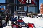 Red Acura race car number 40 in pit lane with city skyscrapers and Chevrolet logo in background on sunny day
