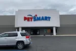 Front view of a PetSmart store with a gray SUV parked outside on a cloudy day.