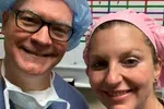 Two healthcare professionals smiling in surgical scrubs and caps in a medical setting.