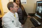 Doctor and assistant reviewing medical scans on computer monitor in clinical office setting