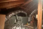 AC Repair in Peachtree Corners by The Air Company of GA. HVAC system with insulated flexible ducts installed in a wooden attic space and supporting pipes.