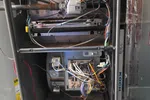 HVAC Repair, Maintenance and Installation in Roswell by The Air Company of GA. Open residential furnace showing internal wiring, circuit board, gas valve, and blower motor components inside metal casing.