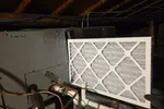 AC Heating Repair on Furnace in Atlanta 30327 by The Air Company of GA.  Air filter installed in a residential HVAC system with visible pipes and insulation in a dimly lit attic space.