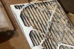 Furnace Heating Repair in Atlanta Decatur 30030 by The Air Company of GA.  Used pleated air filter with dust and debris trapped in the fibers on wooden surface in attic space