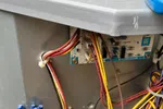 AC Repair and Maintenance in Smyrna 30080 by The Air Company of GA. Open electrical panel with wires, circuit board, and capacitor inside an HVAC unit outdoors.