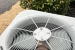 AC Repair in Roswell 30076 by The Air Company of GA.  Outdoor central air conditioning unit with large fan and protective grill sitting near shrubbery.