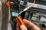 Residential Heating and Furnace Repair in Atlanta Decatur 30033 by The Air Company of GA.  Capacitor with a multimeter and furnace components in the background during electrical testing.