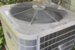 Ac Repair and Maintenance in Smyrna 30080 by The Air Company of GA.   Outdoor air conditioning unit surrounded by green ivy plants next to house siding and piping.
