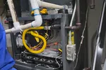 Commercial HVAC Repair in Dunwoody 30338 by The Air Company of GA.  Open Goodman furnace showing internal components, pipes, yellow wiring, and a cordless drill on top.