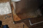 AC Heat Repair in Atlanta 30309 by The Air Company of GA.  Rusty metal drip pan under HVAC unit with white PVC pipes and scattered tools on wooden floor.