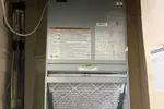 Commercial AC Installation of a Wall Hung Unit by The Air Company of GA.  Indoor view of an HVAC air handler with a visible air filter and connected pipes inside a utility closet.