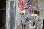 Commercial HVAC Repair in Atlanta 30324 by The Air Company of GA.  Open HVAC metal junction box with various colored electrical wires and connections inside an attic space.
