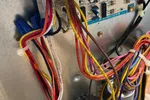 AC Repair and Maintenance in Smyrna 30080 by The Air Company of GA. Close-up of electrical wiring and circuit board inside an HVAC unit with multicolored wires and metal casing.