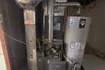 Residential furnace and water heater installation with exposed ductwork and pipes in basement area under construction.  HVAC Repair in Atlanta 30341 by The Air Company of GA.