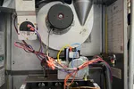 Residential Heating and Furnace Repair in Atlanta Decatur 30033 by The Air Company of GA.  Interior view of a gas furnace showing blower motor, wires, burners, and ventilation duct connections.